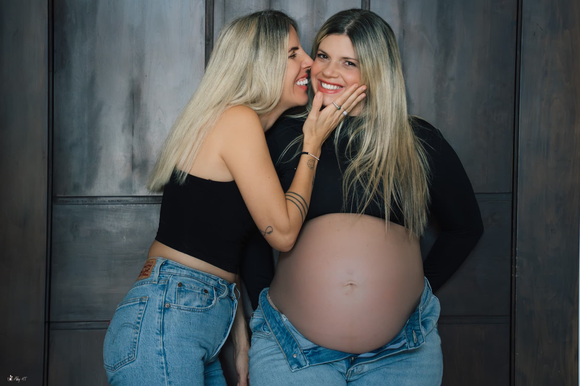 בנות זוג מחייכות יחד על רקע כהה, יד מלטפת את הפנים