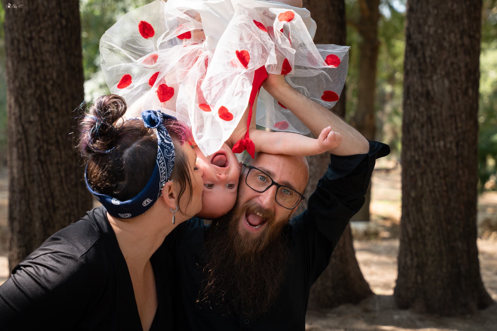 הורים מחזיקים את התינוקת הפוך באוויר וצוחקים