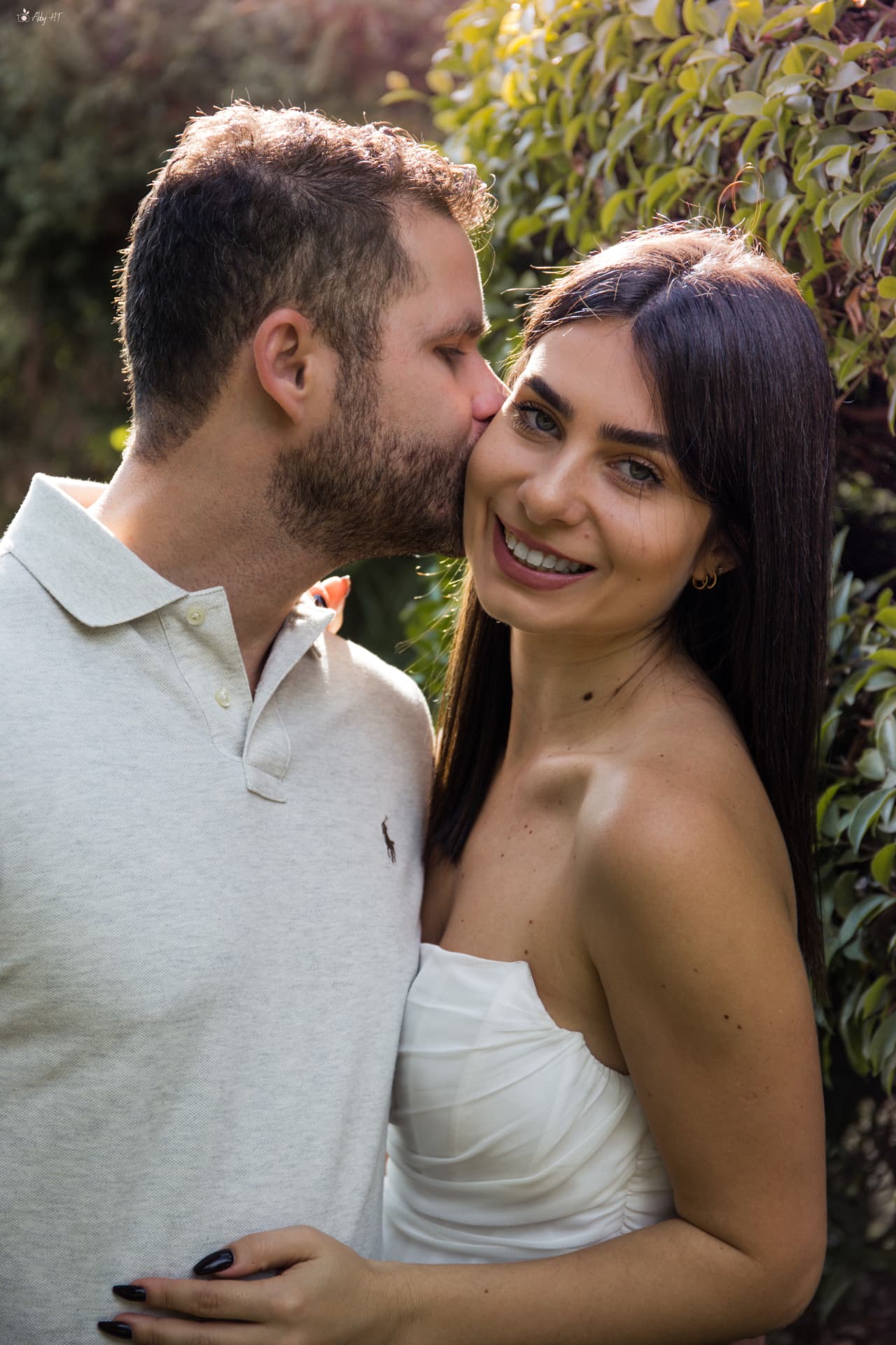 הוא מנשק את לחייה בגן והיא מחייכת למצלמה